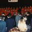 National Boys Choir dressed in red, with their conductor, and in the foreground guests stand around tables