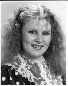 Colette smiles to camera wearing a lace collar and polka dot top