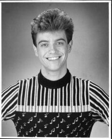 Black and white image of young adult male wearing jumper with piano keys and musical notes