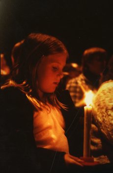 Child looking at her candle in the audience