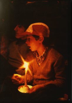 Boy singing in the audience holding a candle