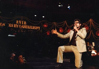 Rolf Harris on bended knee next to the Salvation Army band