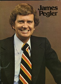 Man in dark suit, light blue shirt and yellow, red and white striped tie