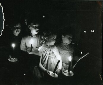 Four children hold candles at Carols