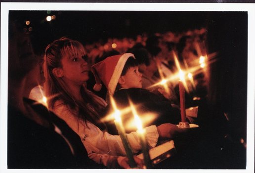 Woman holds candle and boy in her lap