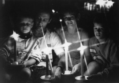 Two boys, man and woman hold candles at Carols by Candlelight