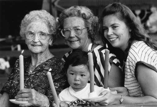 Three women and child holding candles