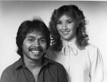 Seated male and standing female smile to camera