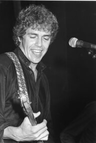 Side view of man playing guitar with microphone in front of him
