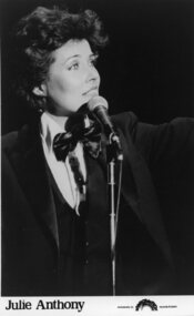 Julie Anthony dressed in a tuxedo with a microphone