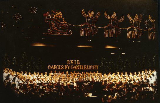 Choir and orchestra underneath Santa and reindeer lights