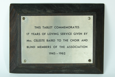 Silver plate with black writing attached to black wood