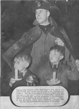 Serviceman uses his coat to keep rain off two boys with candles