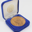 Bronze coloured medallion with illustrations in box