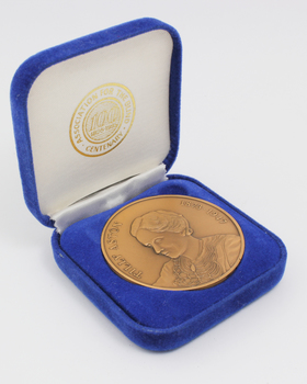 Bronze coloured medallion with illustrations in box