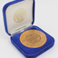 Bronze coloured medallion with illustrations in box