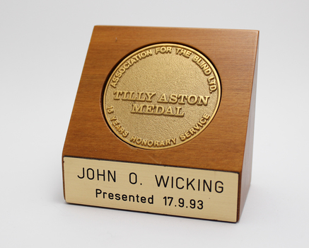 1 blonde wooden stand with gold tone inlaid medallion and nameplate on front 'John O. Wicking Presented 17.9.93'