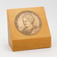 1 blonde wooden stand with gold tone inlaid medallion
