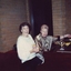 Two women sit at the piano in the room