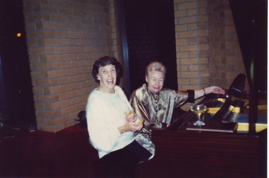 Two women sit at the piano in the room