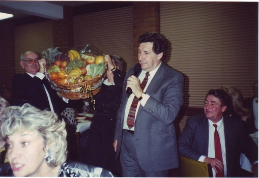 Bob Davis and helper hold up a giant fruit basket