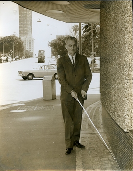 Man walks along William Street using white cane