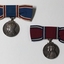 2 silver medals hanging from blue or red ribbon tied into bow.