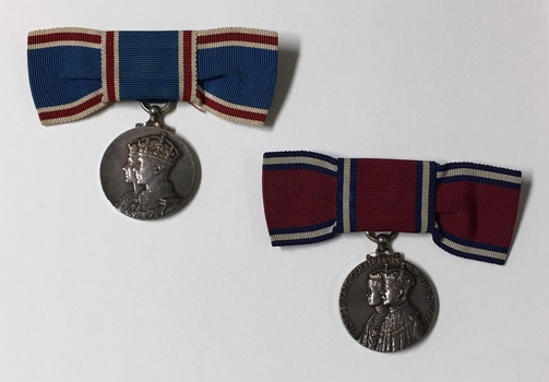 2 silver medals hanging from blue or red ribbon tied into bow.