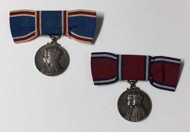 2 silver medals hanging from blue or red ribbon tied into bow.