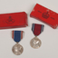2 silver medals hanging from a red or blue ribbon with blue or red and white edging with red medal boxes.
