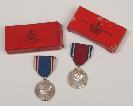 2 silver medals hanging from a red or blue ribbon with blue or red and white edging with red medal boxes.