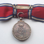 Rear of red ribbon tied into bow with silver medal hanging 
