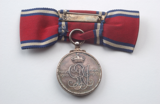 Rear of red ribbon tied into bow with silver medal hanging 
