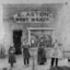 Four people stand outside of a shop with a sign E Aston Boot Maker