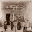 Four people stand outside of a shop with a sign E Aston Boot Maker