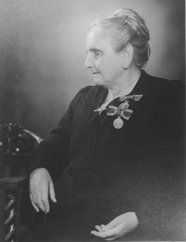 Seated older lady with two coronation medals pinned to her left breast