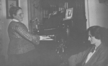 Woman playing organ whilst another woman listens