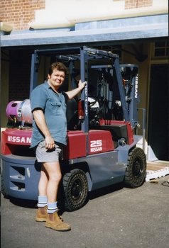 Unknown man stands next to a forklift