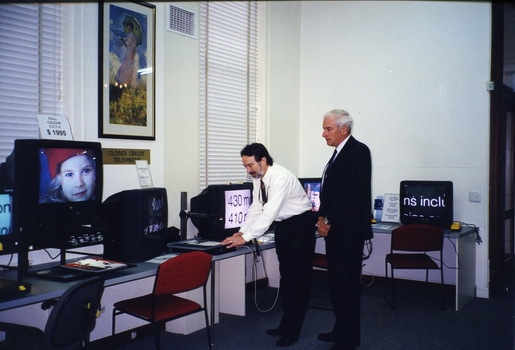 Peter Lynam with an unidentified man at the screen magnifier display 