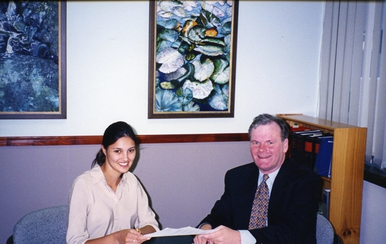 Geoff Melvin passing a document to a unidentified female