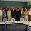 Group of people standing behind tables and chairs set in open rectangle layout
