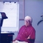 Man seated as he uses an overhead projector