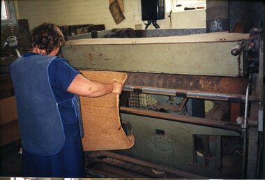 Unidentified female with a machine on the factory floor