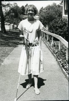 Woman using white cane walking up to main reception at Enfield
