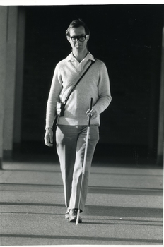 Man with sonic guide and white cane walking in a building