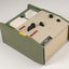 Green and cream box with black levers and removable plastic cartridge housing magnetic tape.