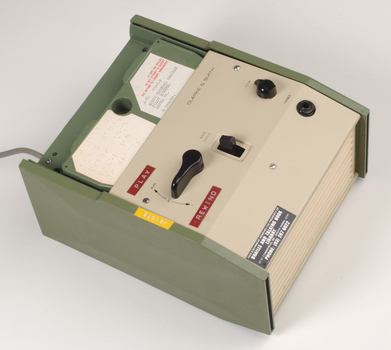Green and cream box with black levers and removable plastic cartridge housing magnetic tape.