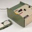 Green and cream box with black levers and removable plastic cartridge housing magnetic tape.