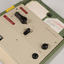 Green and cream box with black levers and removable plastic cartridge housing magnetic tape.