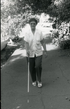 Woman walking with white cane on footpath